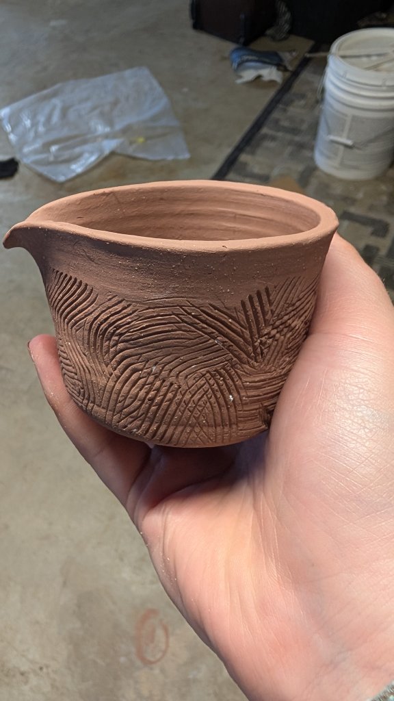 Carved textured clay pour spout vessel in hand