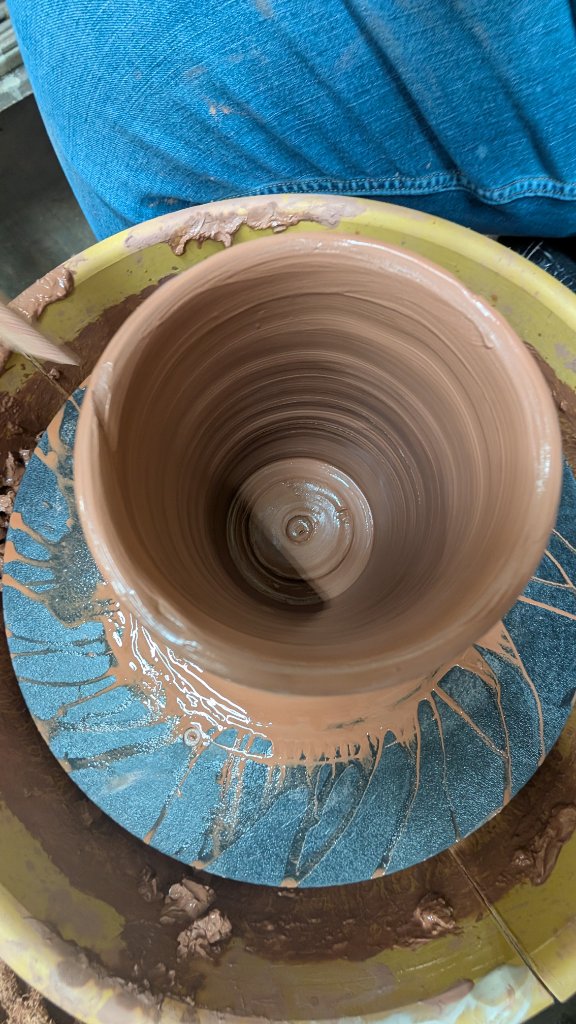 Overhead view of clay being thrown on wheel