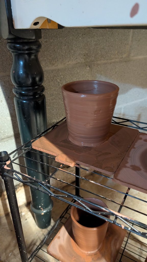 Straight-sided clay cup on shelf