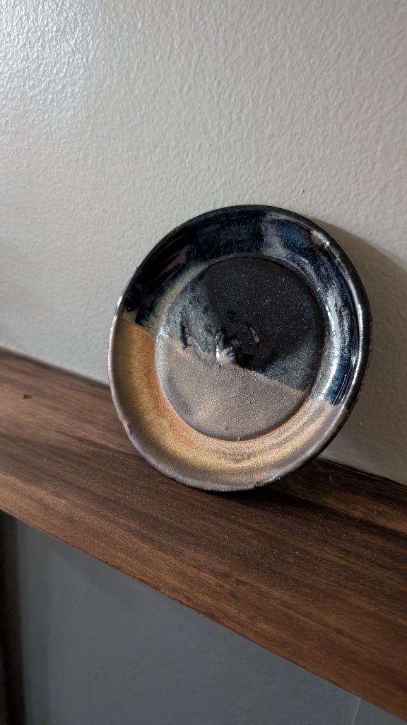 Blue and tan glazed small plate on wood shelf
