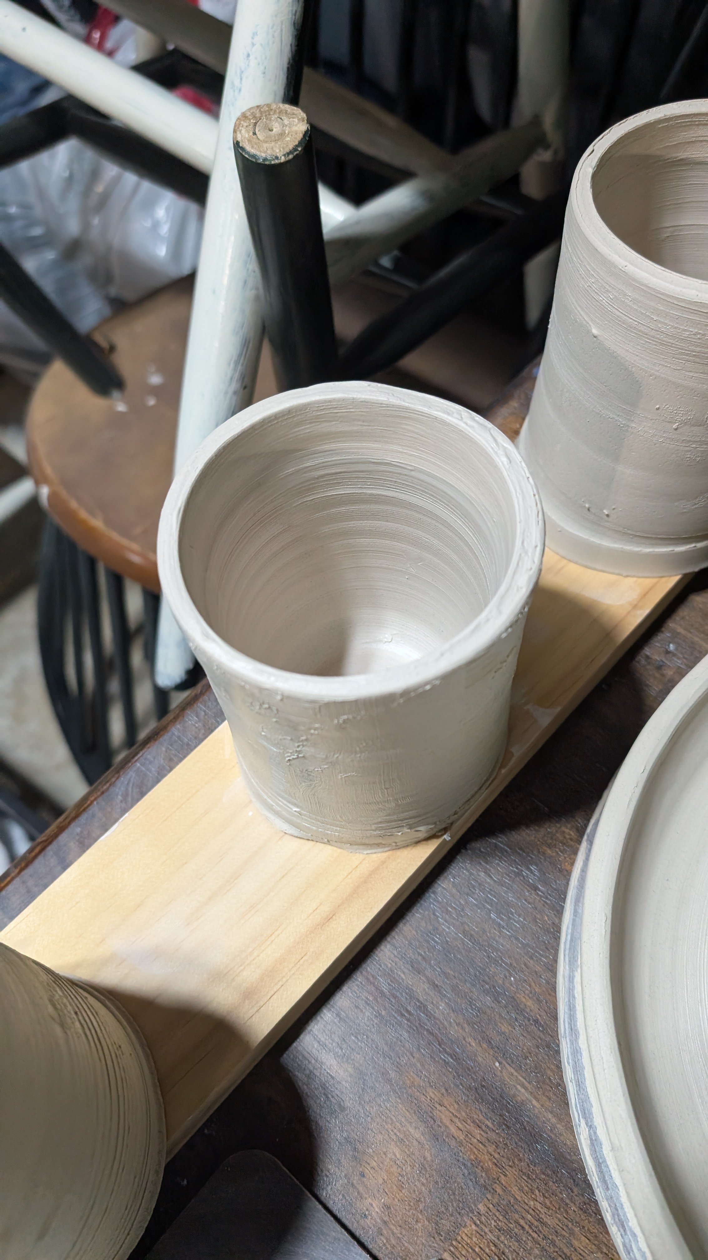 Hand-thrown clay cup drying on wood board