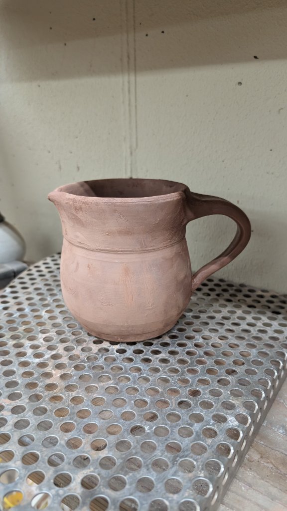 Clay mug with handle on kiln shelf
