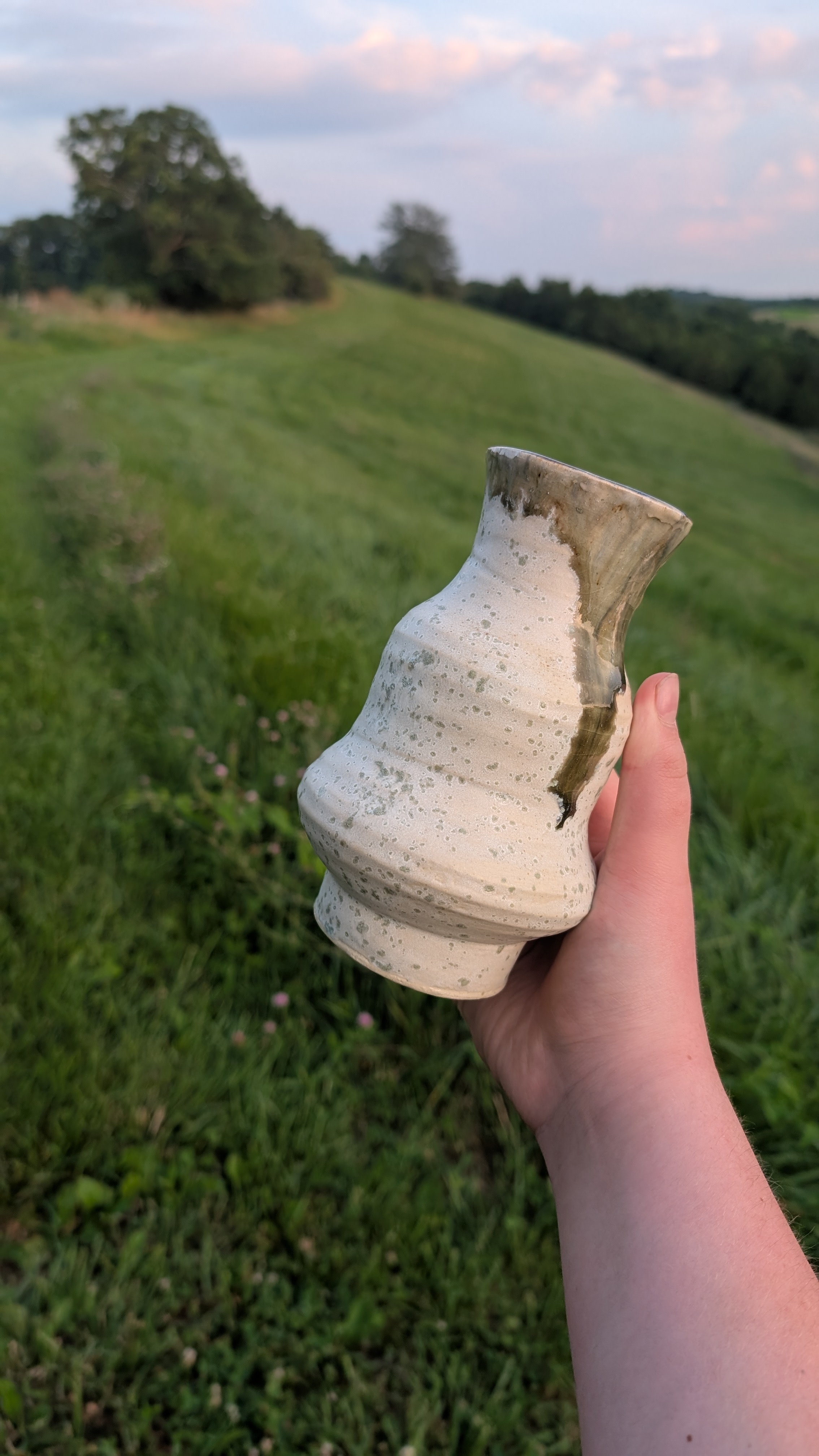 Speckled vase with olive drip held at dusk