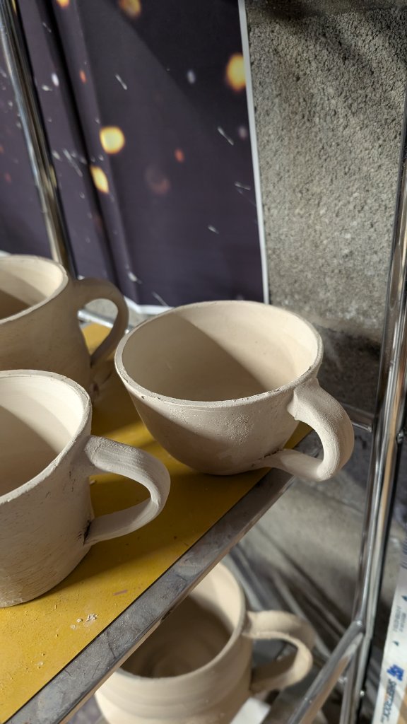 Unfired clay mug with handle close-up on rack