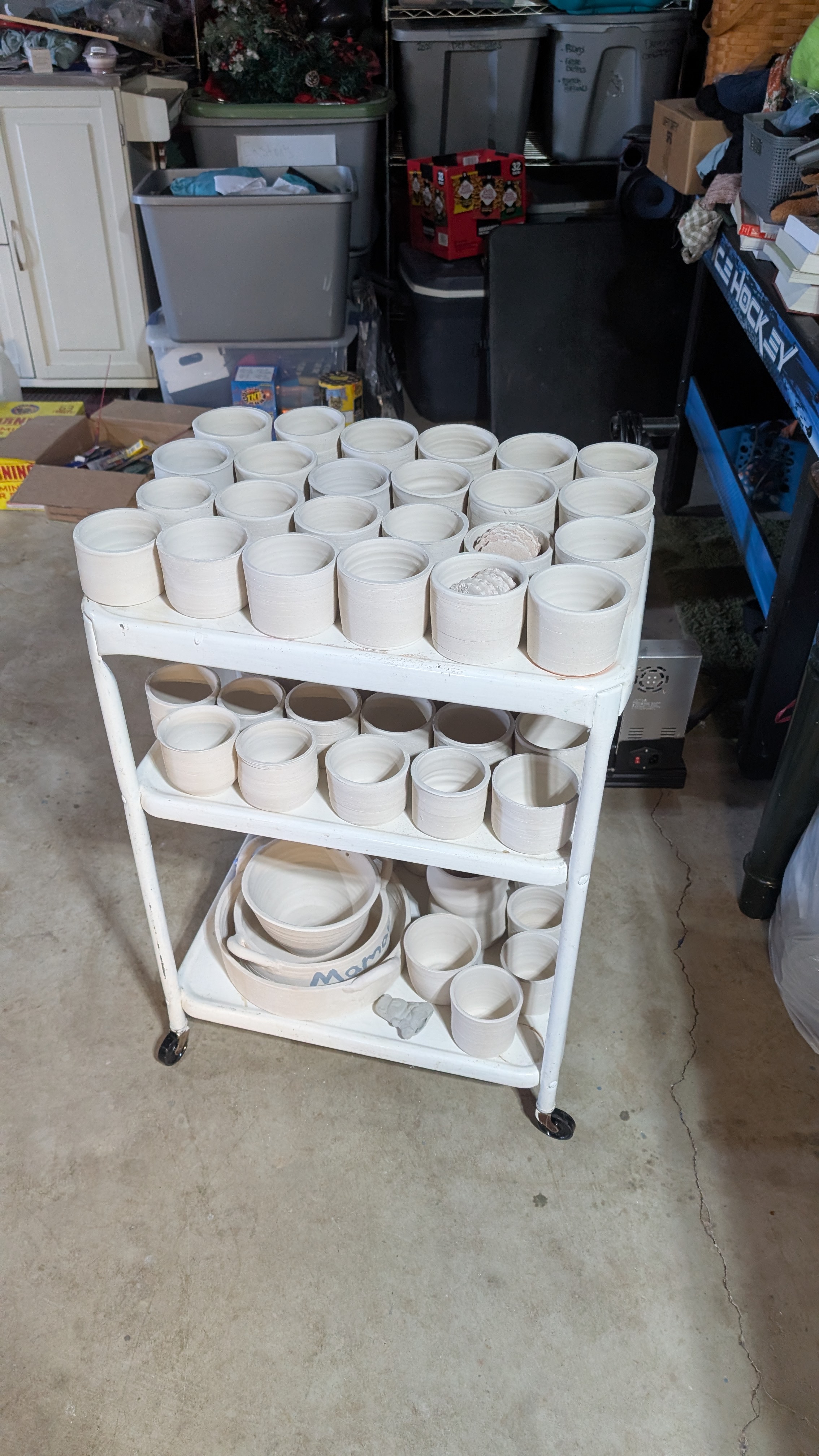 Three-tier cart filled with unfired greenware mugs
