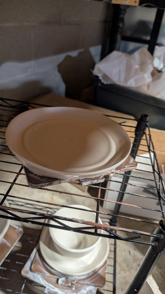 Clay plate drying on studio shelf
