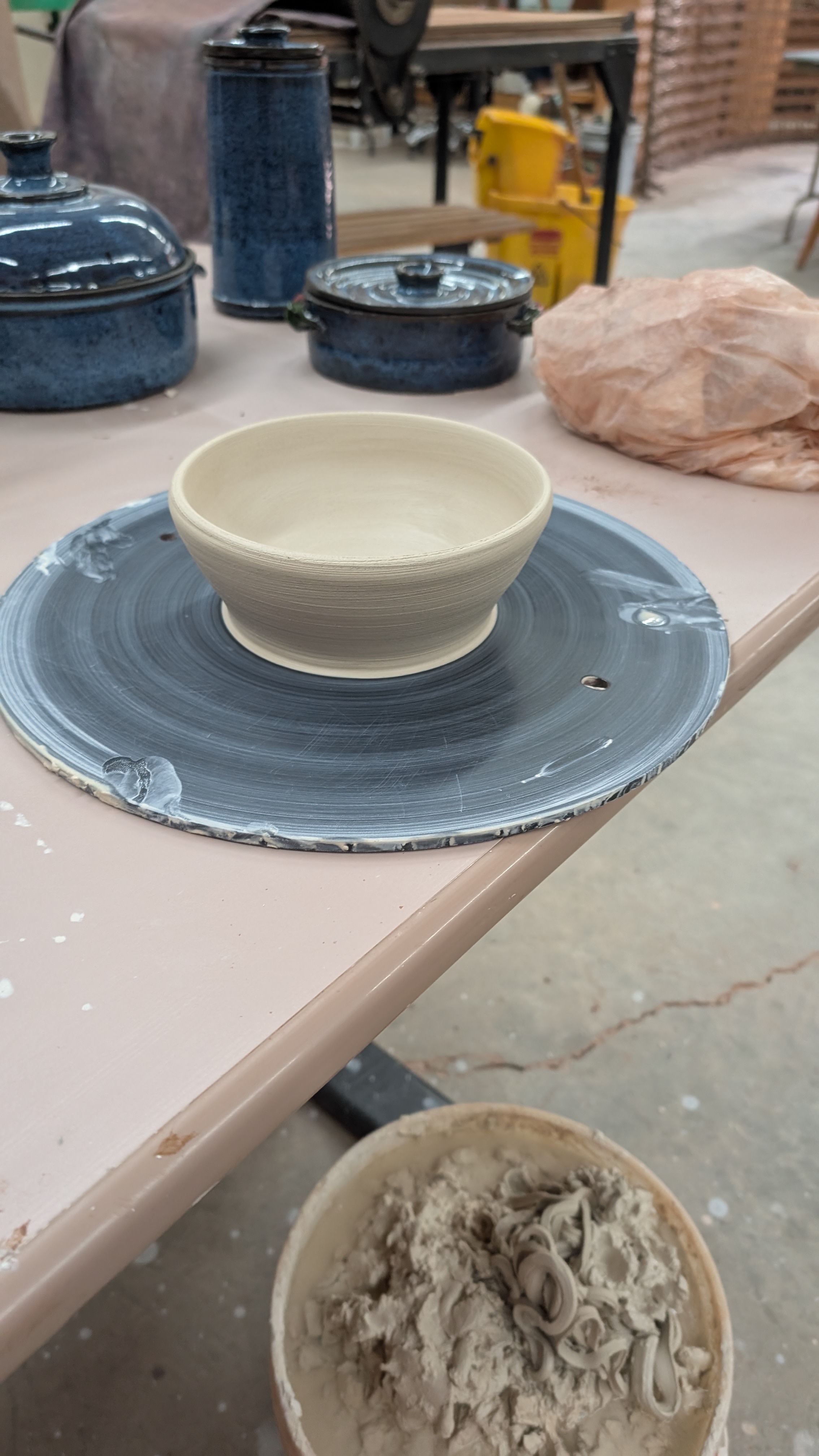 Unfinished ceramic bowl centered on wheel bat