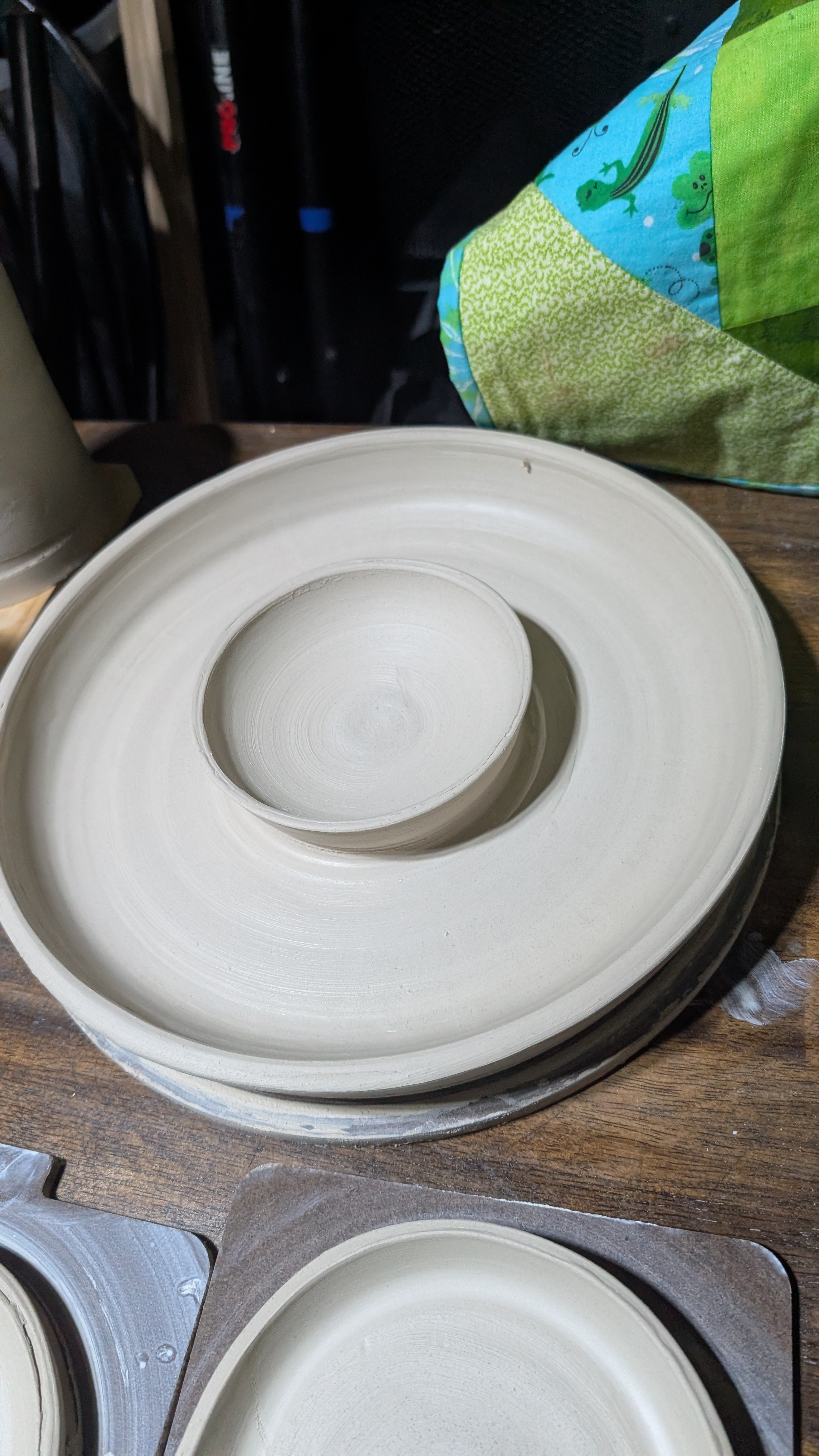 Unfired bowl nested in plate on wooden board