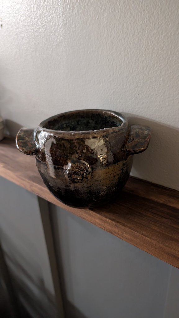 Dark metallic glazed bowl with tab handles on wood shelf