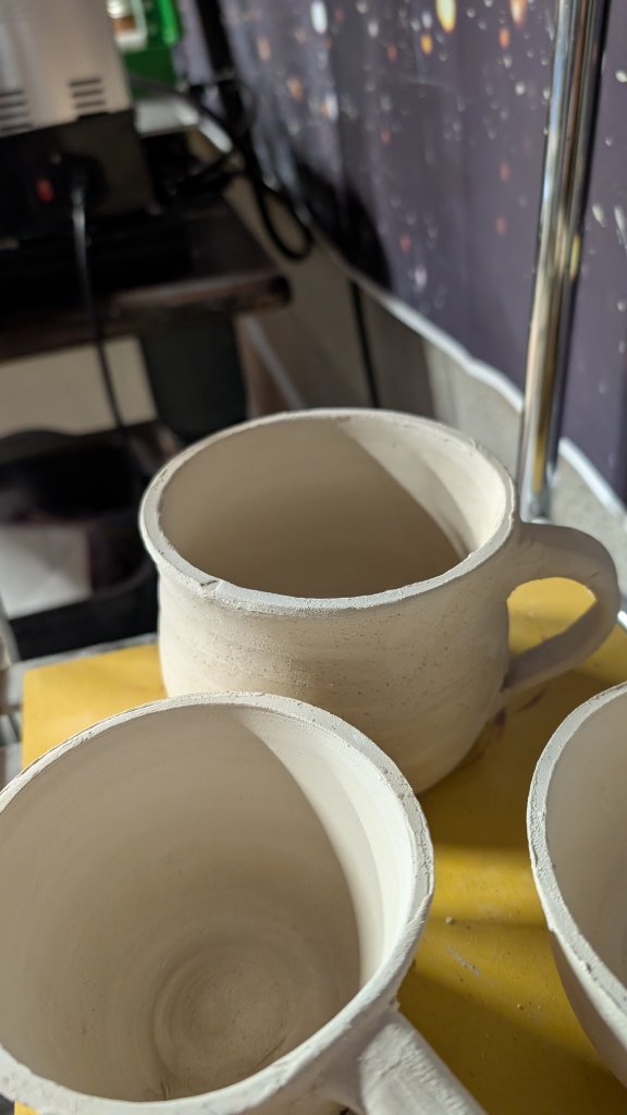 Unfired clay mug detail on studio rack
