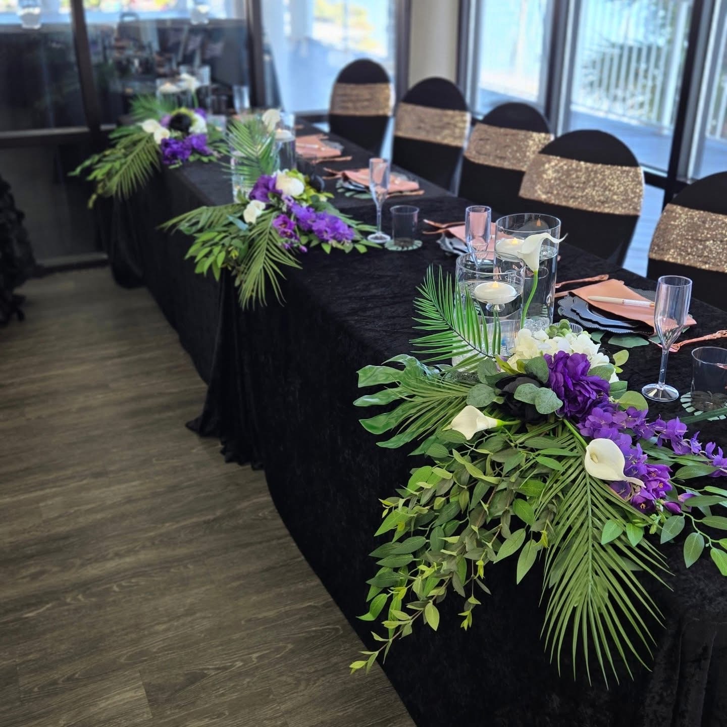 Elegant black table with purple floral centerpiece and champagne glasses