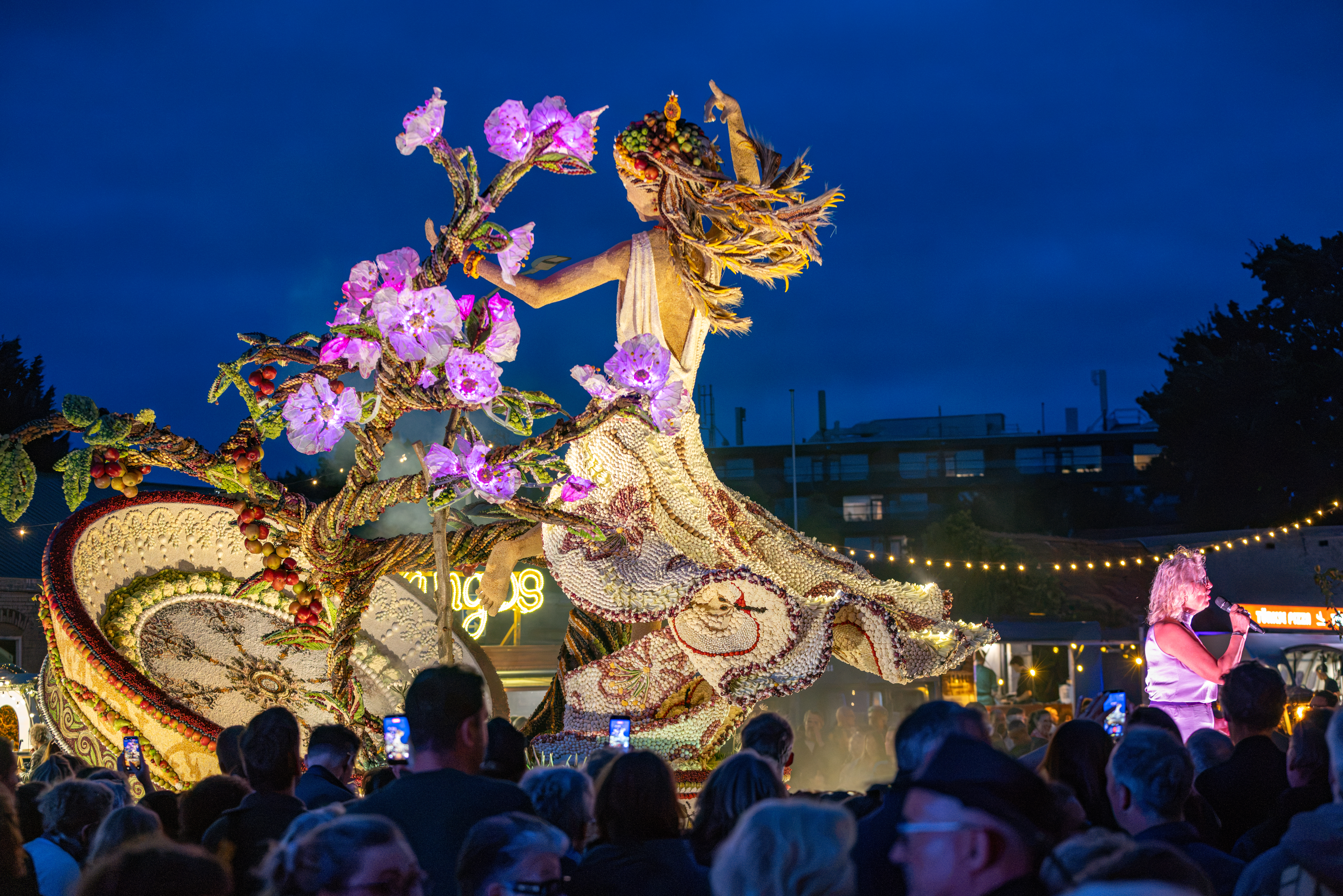 Verlicht fruitkunstwerk met bloemen en bezoekers tijdens de avond van Fruitfestival Tiel 2026