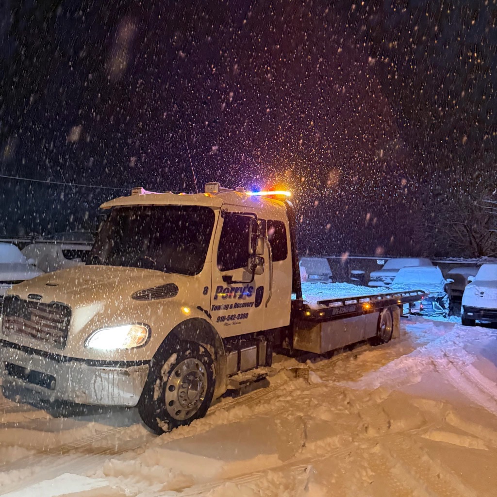 Perry's red flatbed towing a Grove EMS ambulance
