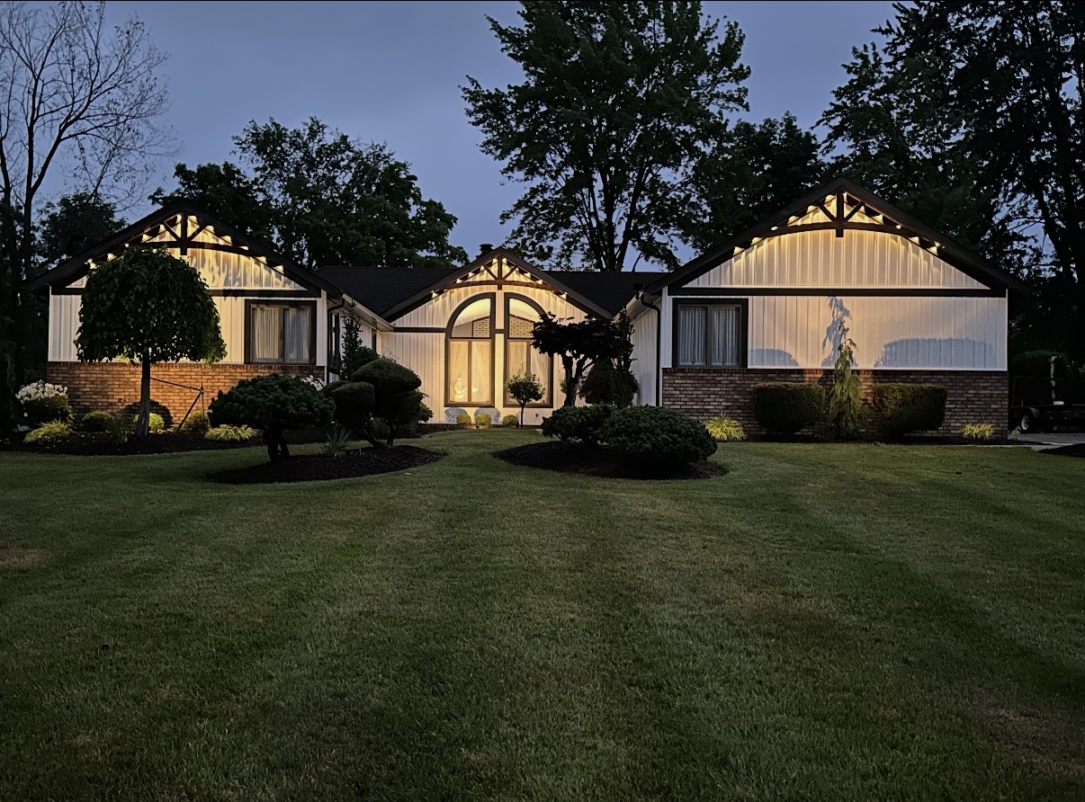 Seasonal holiday lighting installation on a home at dusk