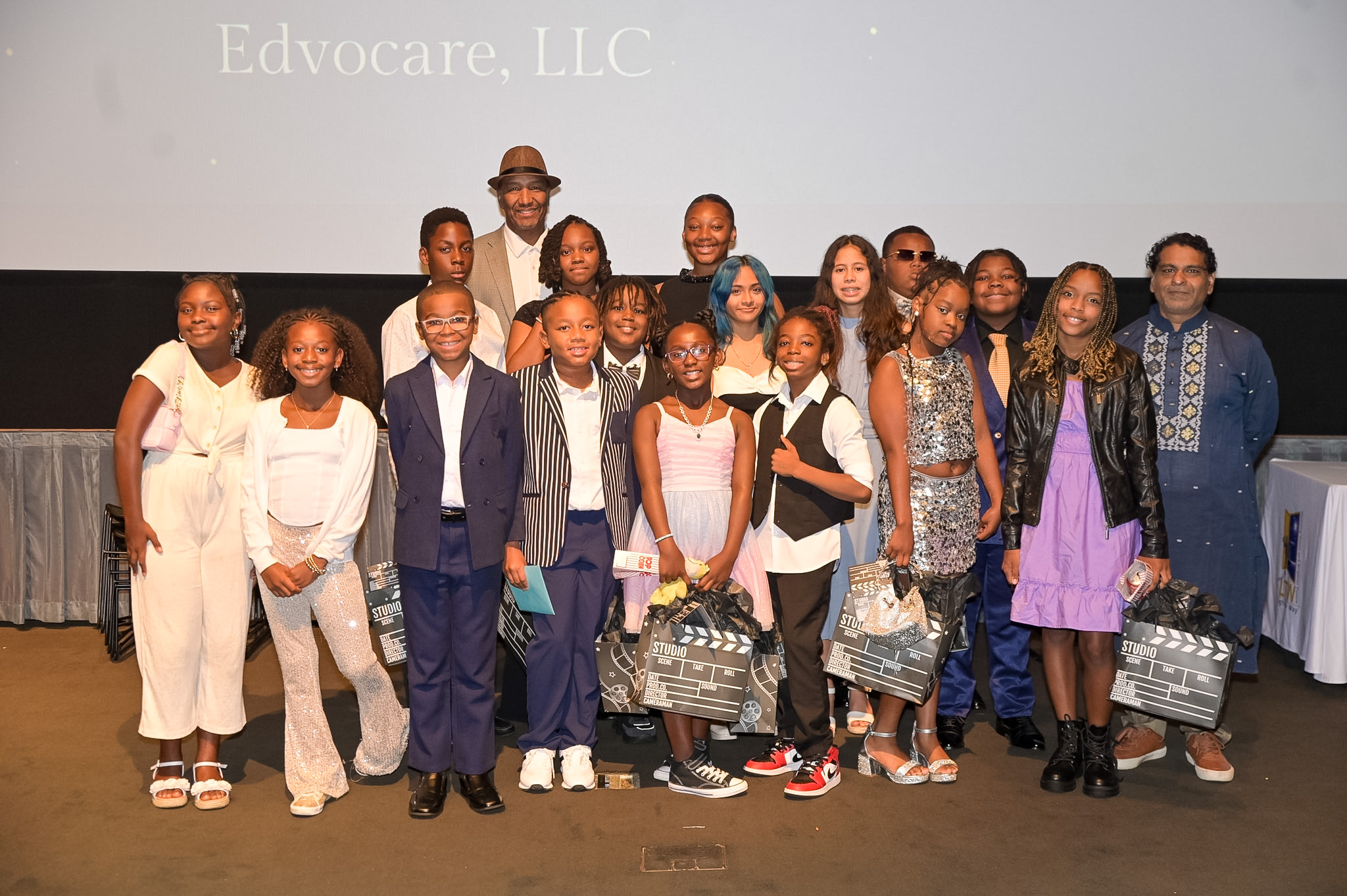 Group of children and adults holding movie clapperboards on stage at the 2026 Red Carpet Premiere