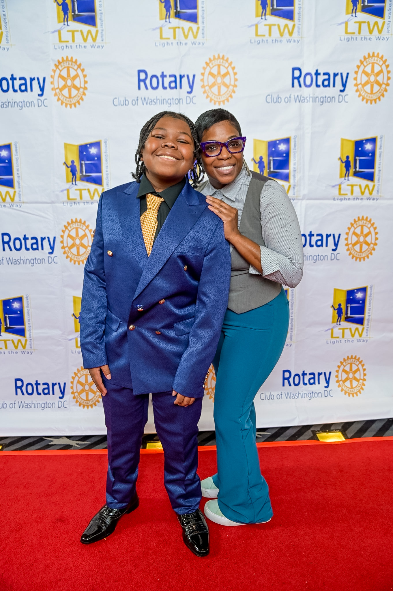 Young boy in a blue suit and an adult woman posing at the 2026 Red Carpet Premiere