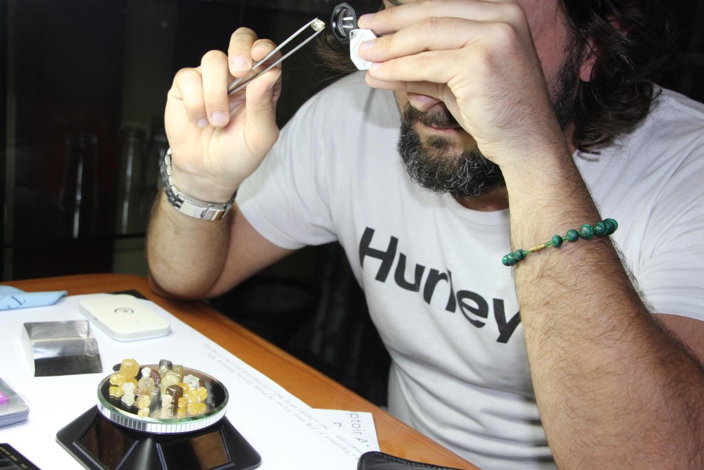 Eliahi examining a gemstone through a jeweller’s loupe