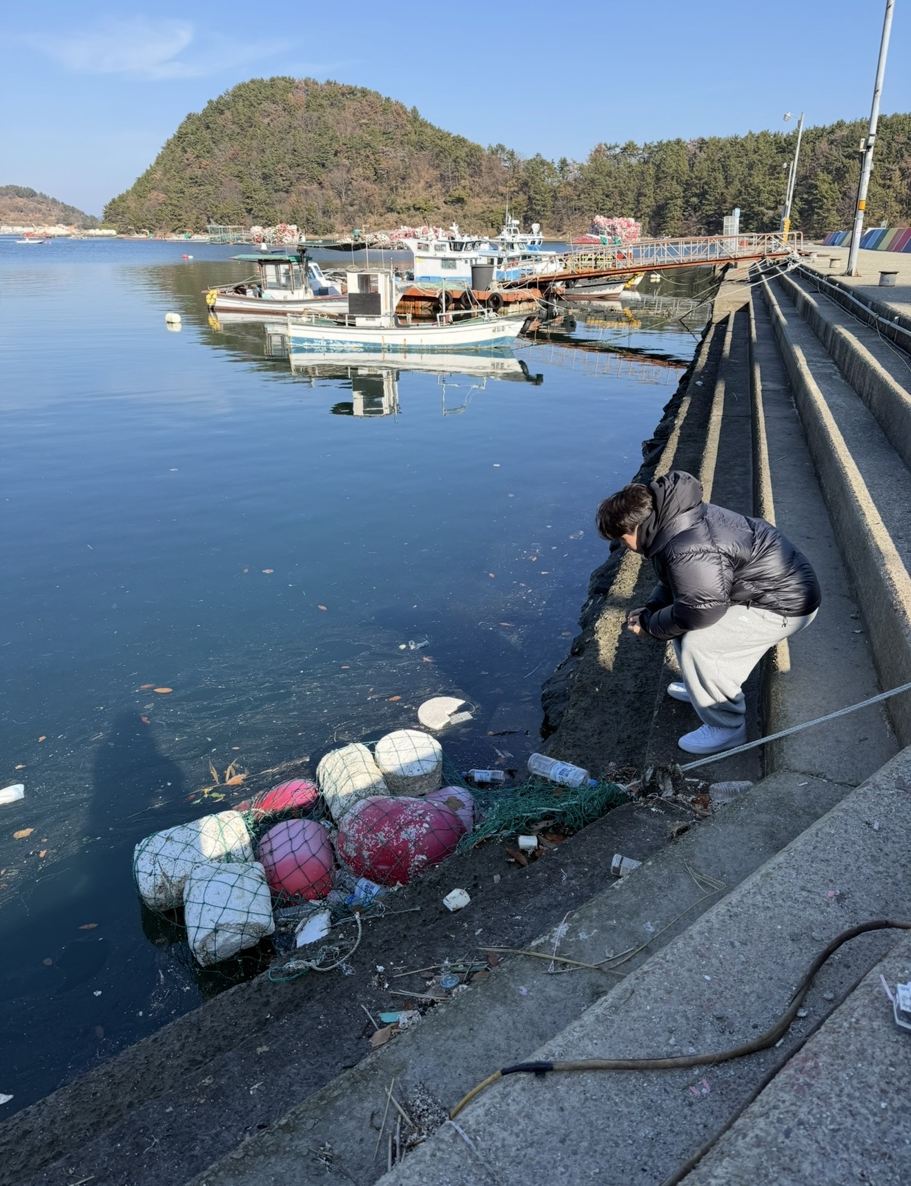 Ambassador collecting plastic debris and fishing buoys from a Jeju harbour during the beach clean-up