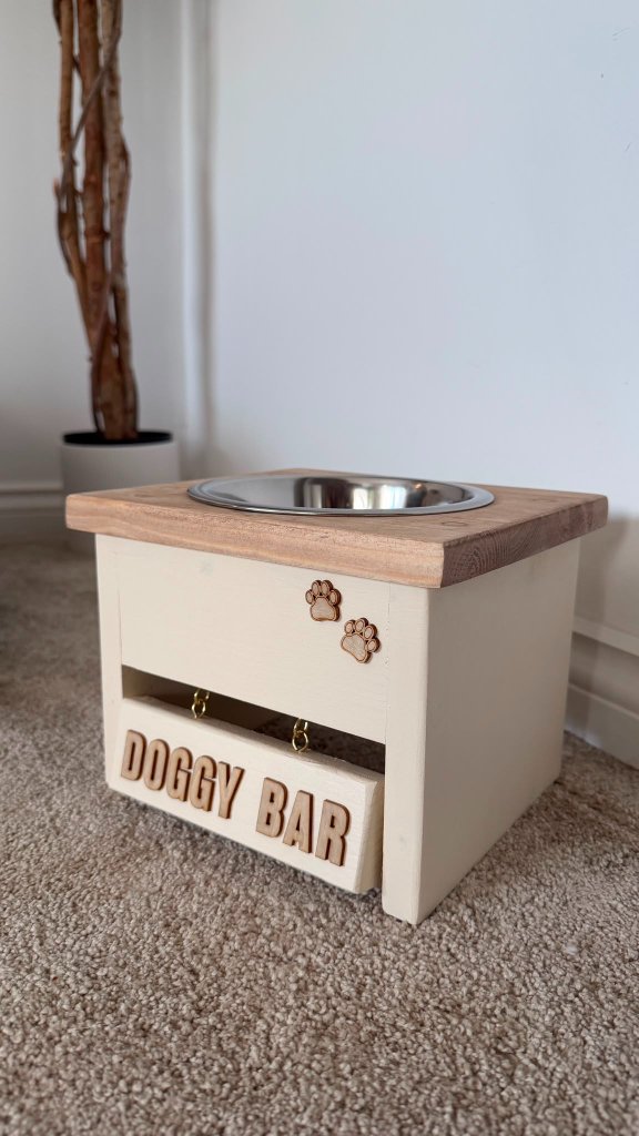 The Doggy Bar feeding station in the Retreat Room at House of Paws Retreat — a stainless water bowl on a wooden top, paw print details and raised 'DOGGY BAR' signage for a playful, designer touch