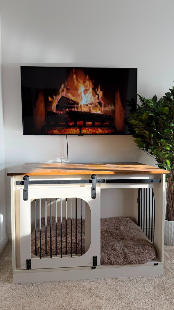 The cosy crate area in the Retreat Room at House of Paws Retreat — a wooden crate with sliding barn doors, a fluffy dog bed inside and a calming fireplace video for a den-like, comforting nap