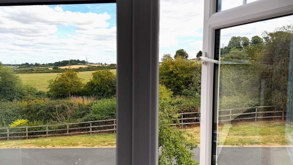 Peaceful countryside view through a window at House of Paws Retreat — fields and hedgerows looking out toward Grassmoor Country Park near Chesterfield, Derbyshire