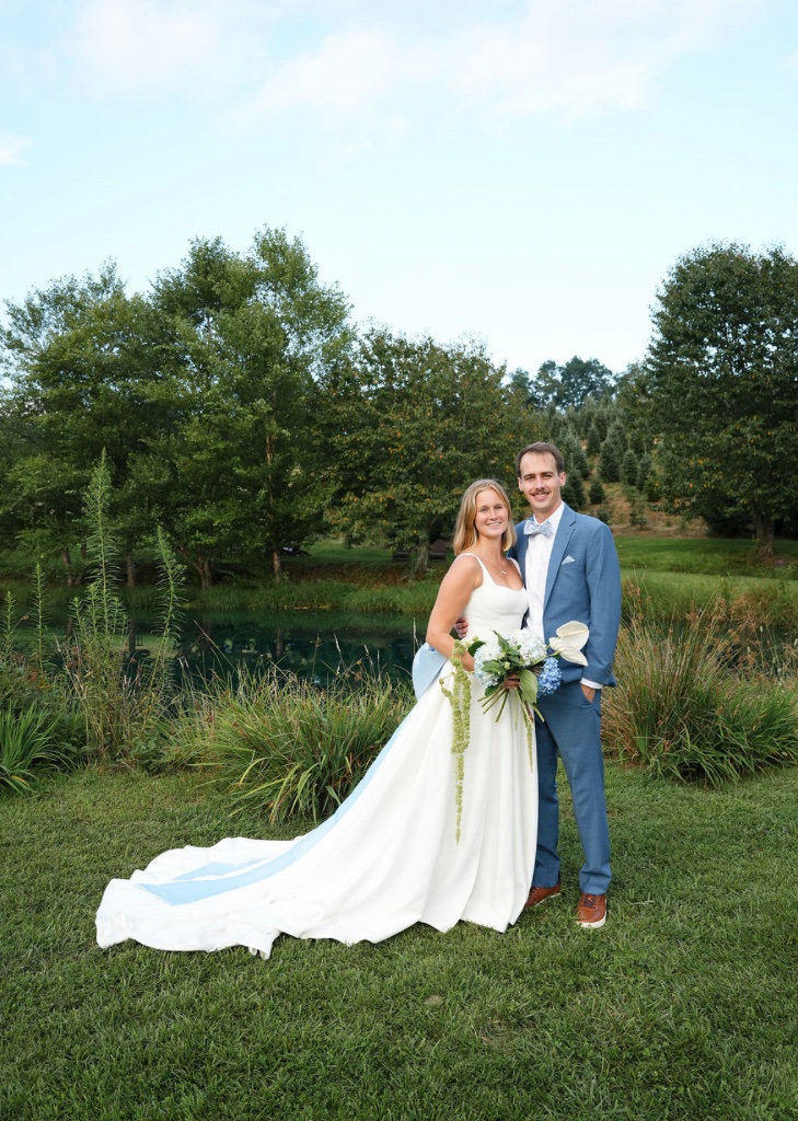 Bride and groom portrait by pond with blue hydrangea and anthurium bouquet