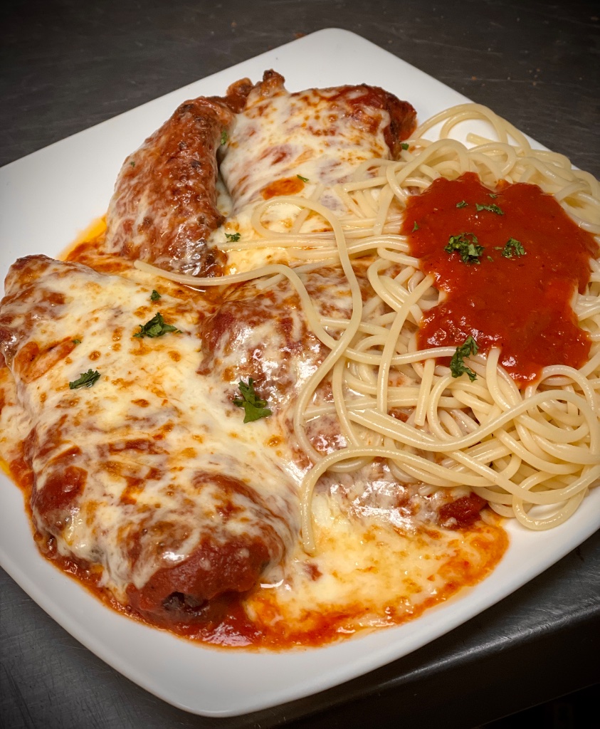 Fresh baked eggplant parmigiana and ravioli in rich marinara sauce with bubbling mozzarella