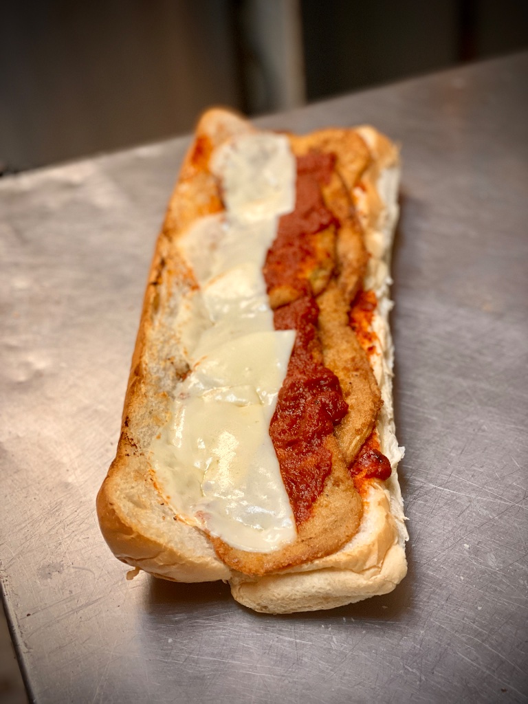 Classic Italian grinder sandwich with melted provolone and Italian meats on a rustic cutting board