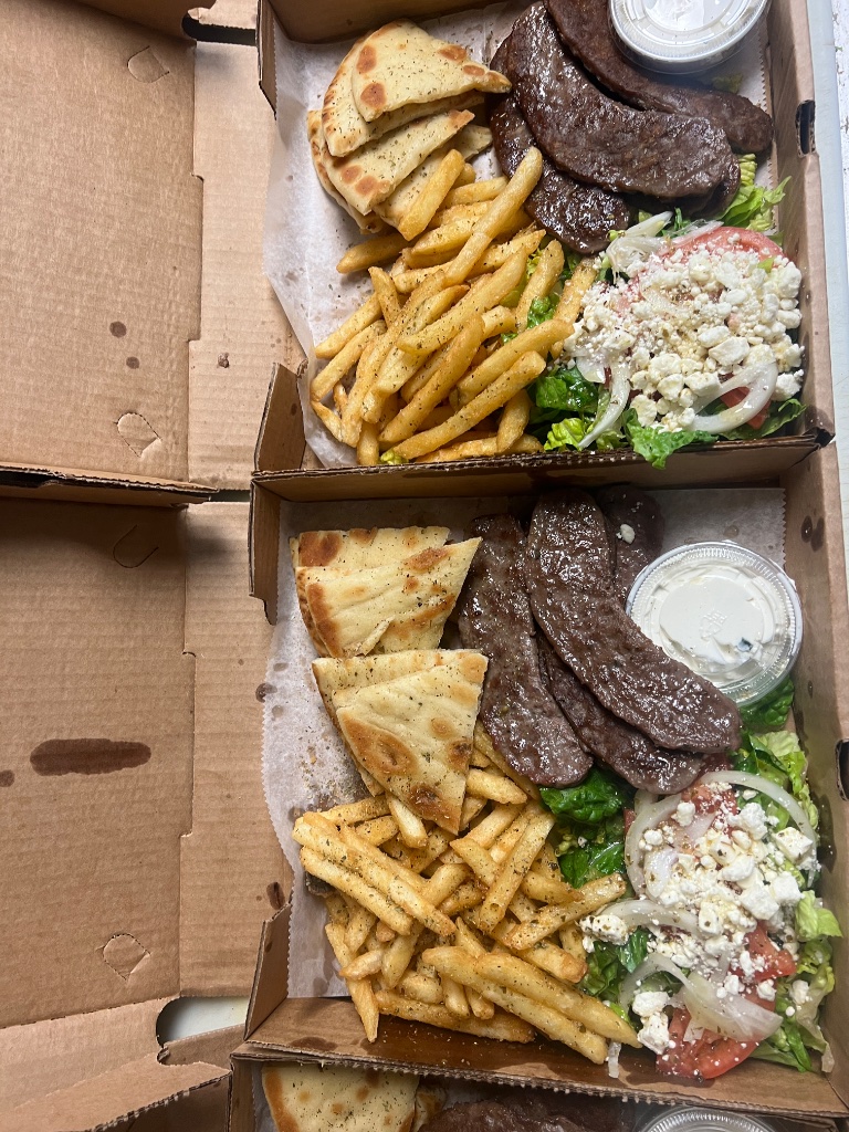 Greek gyro platter with pita bread, sliced gyro meat, feta cheese, tzatziki sauce and golden fries