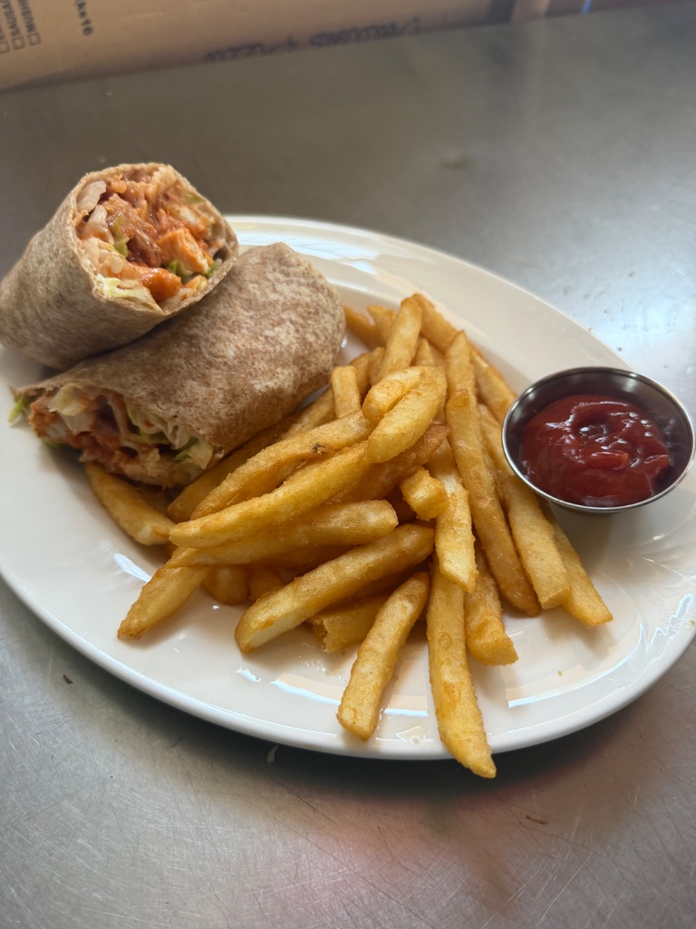 Chicken wrap halves with fries and ketchup on a white plate