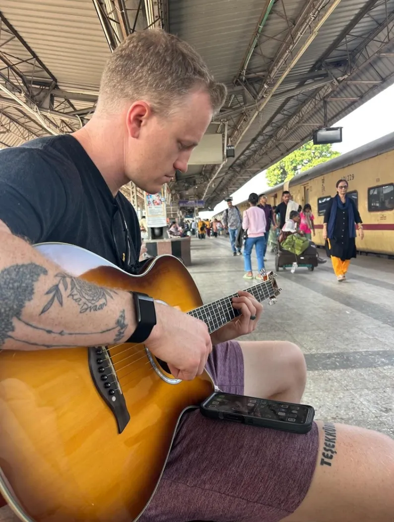 James playing guitar at the train station