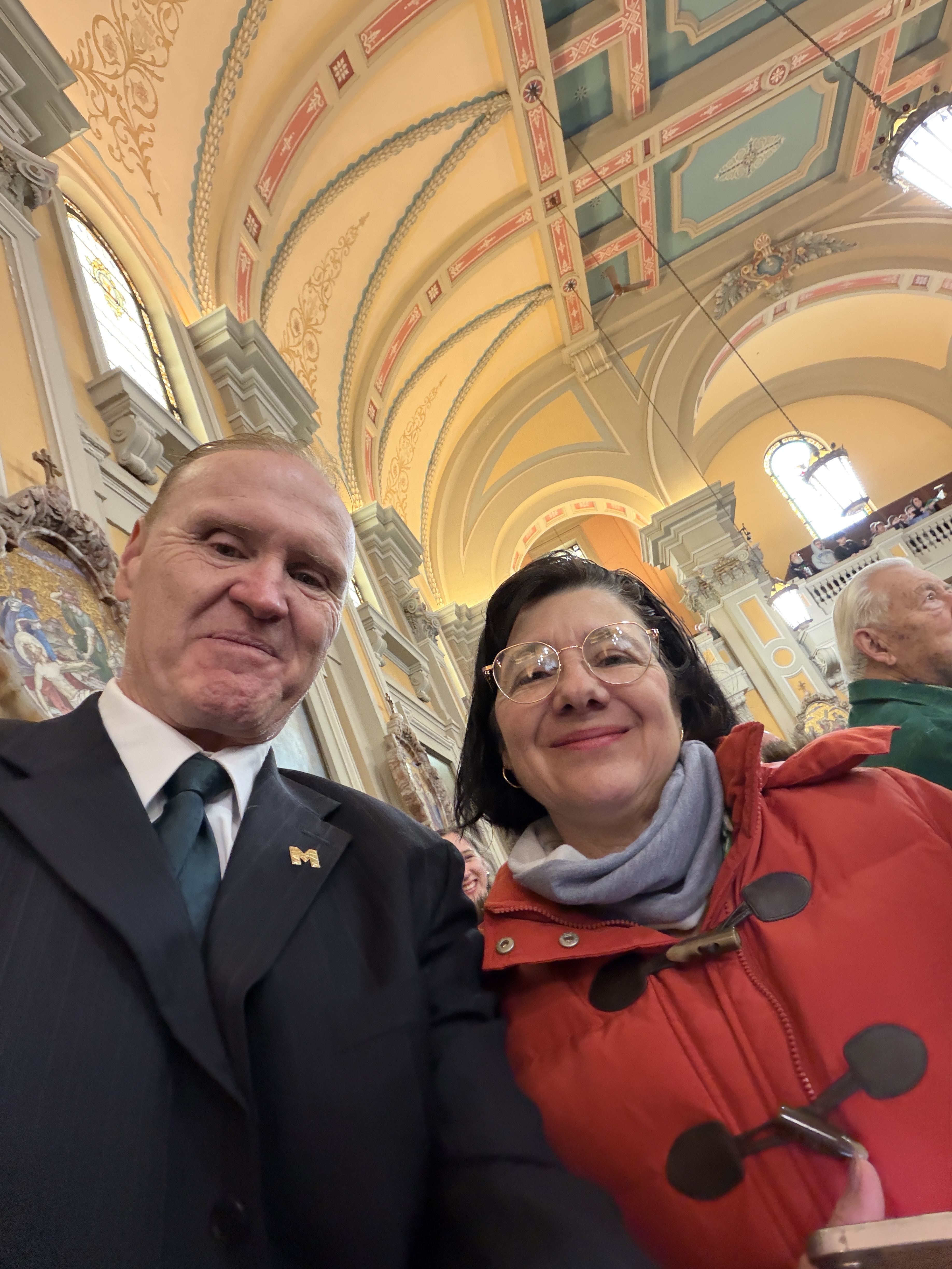 Marisa and Dan posing inside a church or cathedral with vaulted ceilings and stained-glass windows