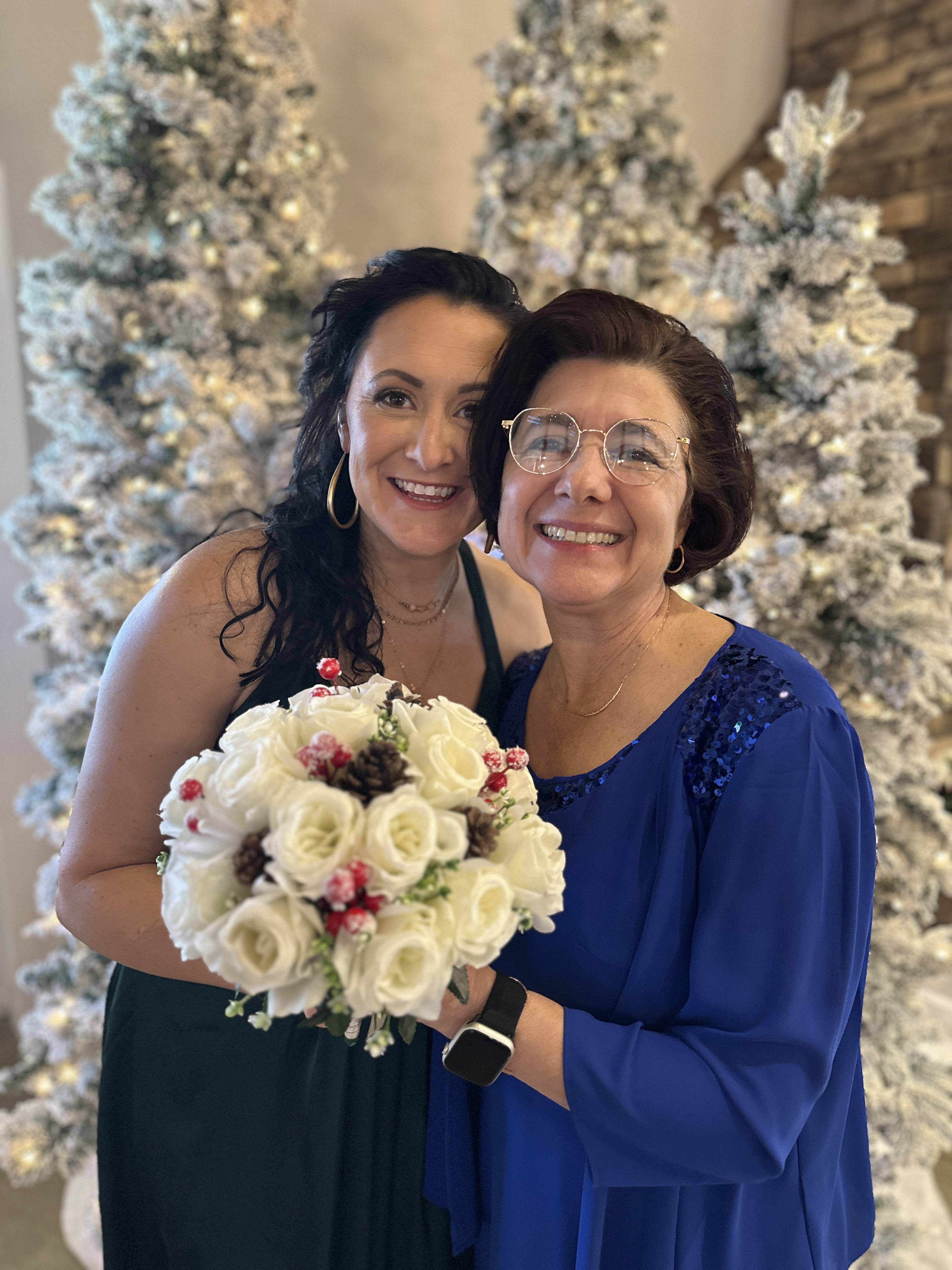 Marisa with family during the holidays beside decorated Christmas trees