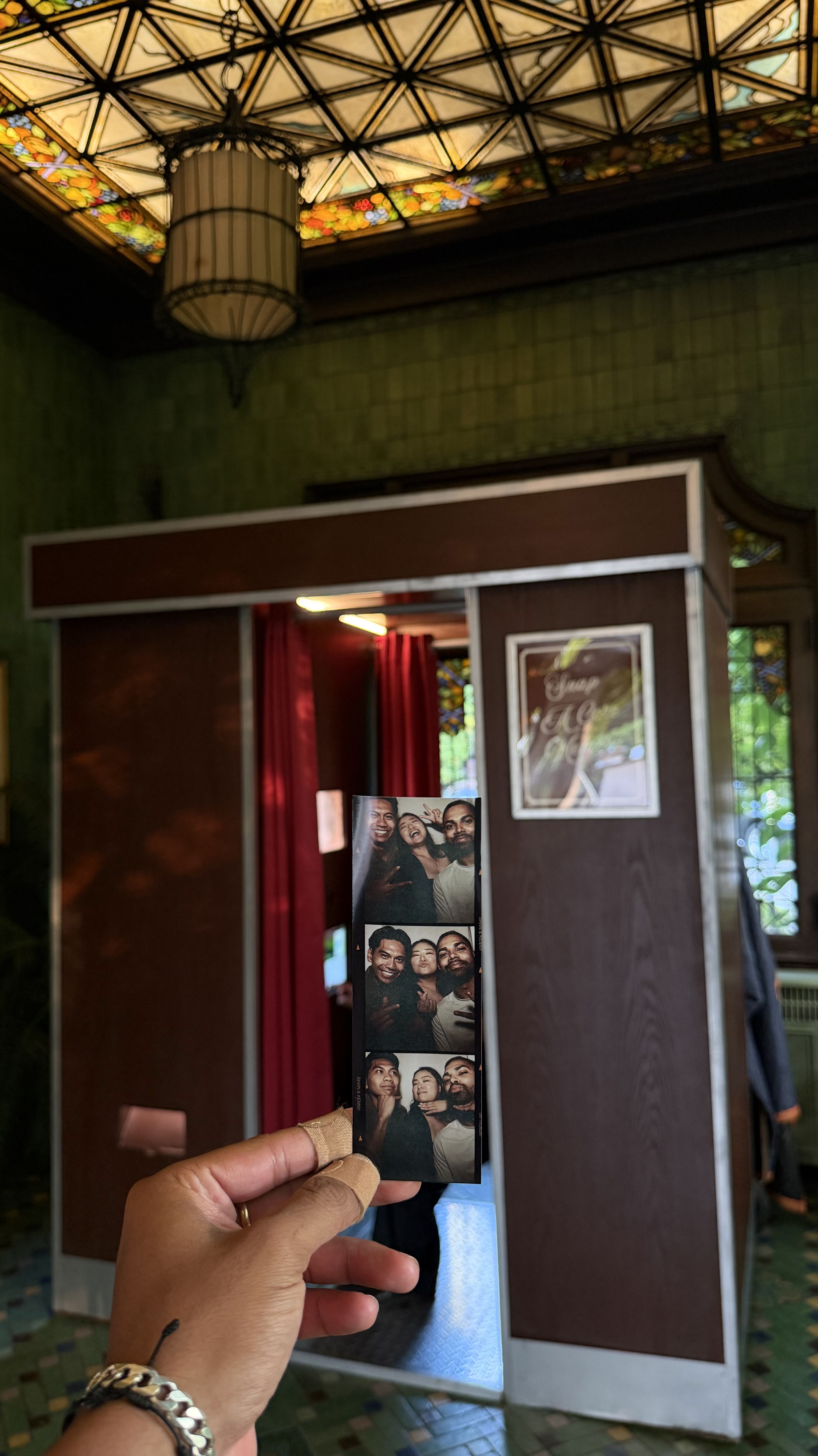 A guest holding a printed photo strip in front of The Retro Booth's vintage cabinet inside a historic venue