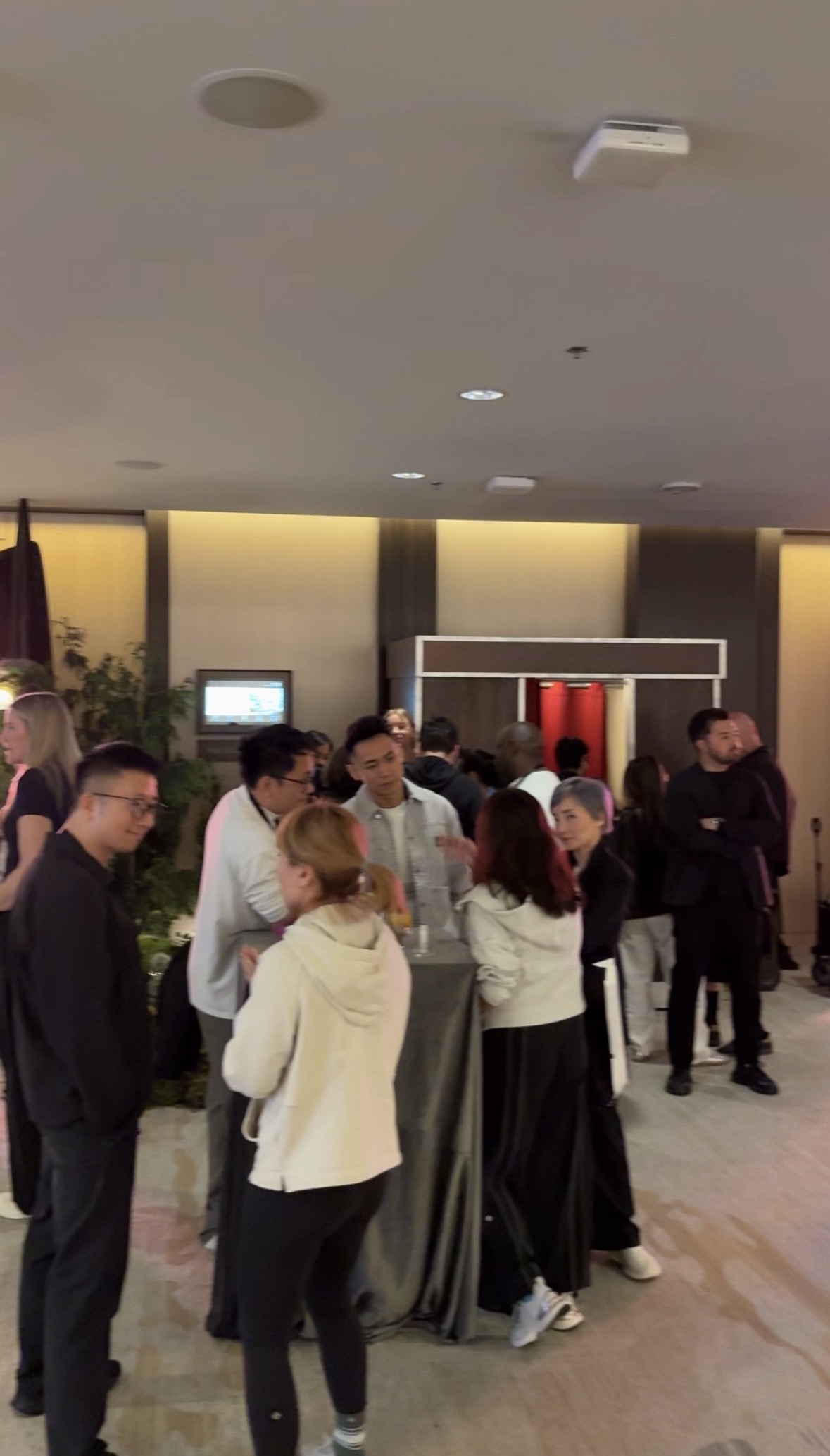 A crowd of guests mingling near The Retro Booth's enclosed vintage cabinet at a corporate holiday party in Vancouver