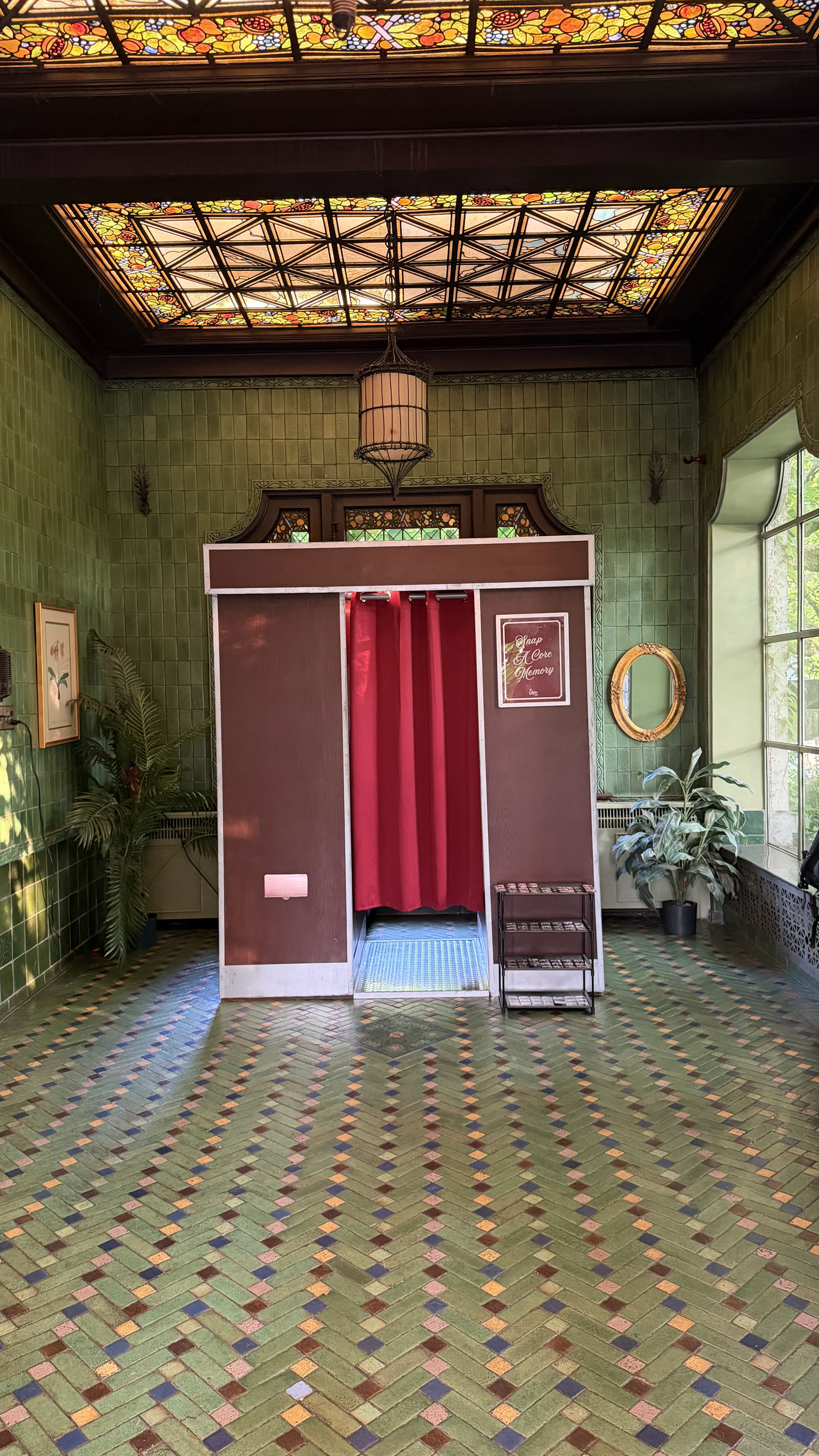 The Retro Booth's enclosed vintage photo booth set up inside a historic venue with a stained glass ceiling and mosaic tile floor