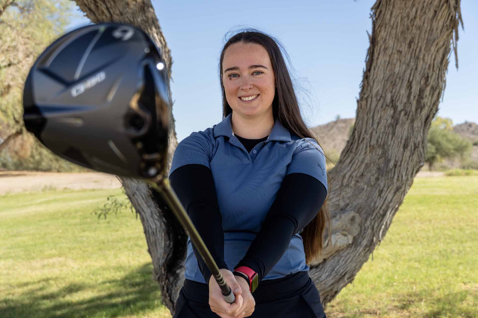Avery Arnold, Assistant Golf Professional at Junior National, smiling on the course while holding a driver.