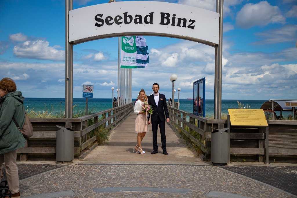 Fotograf Binz Hochzeit – Brautpaar vor dem Seebad Binz Schild an der Seebrücke