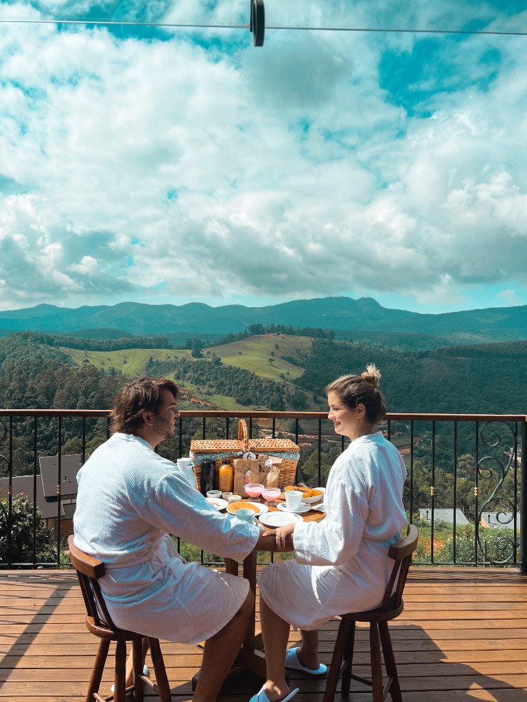 Bia e Pedro em uma varanda com vista para as montanhas