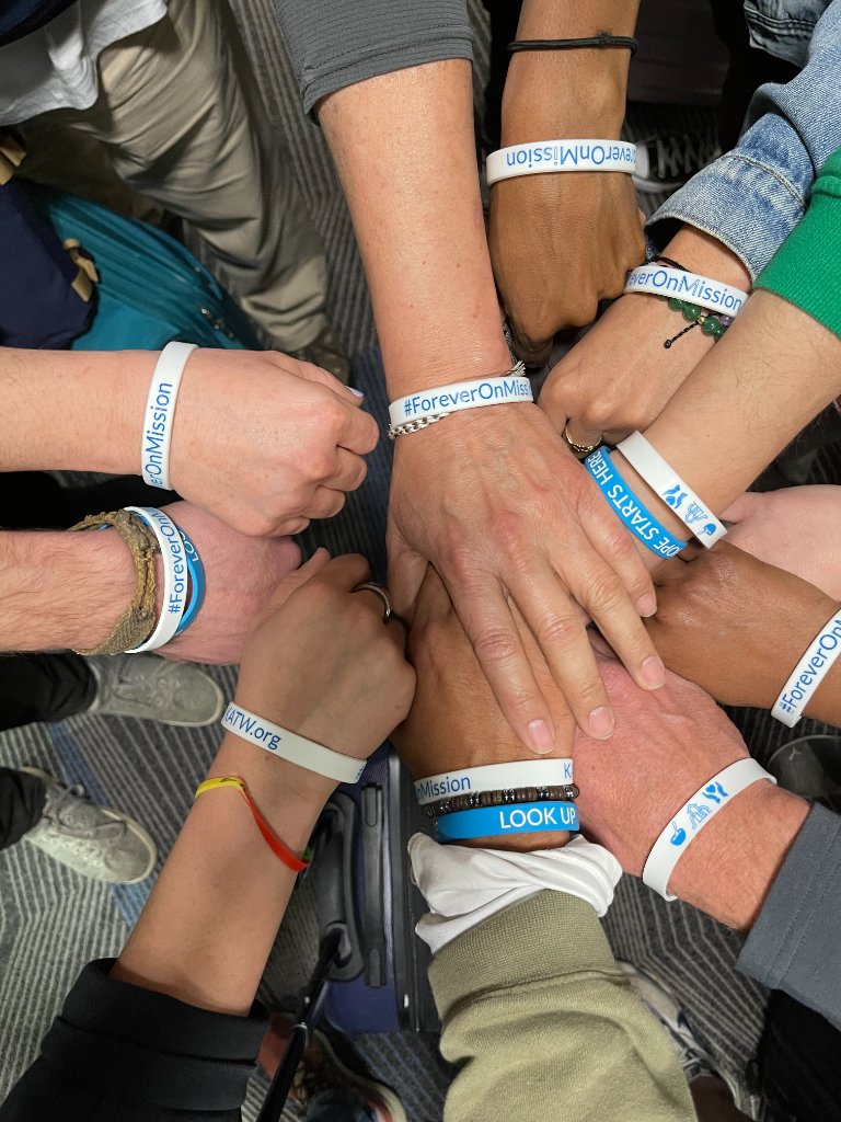Mission team hands together wearing #ForeverOnMission and KATW.org wristbands