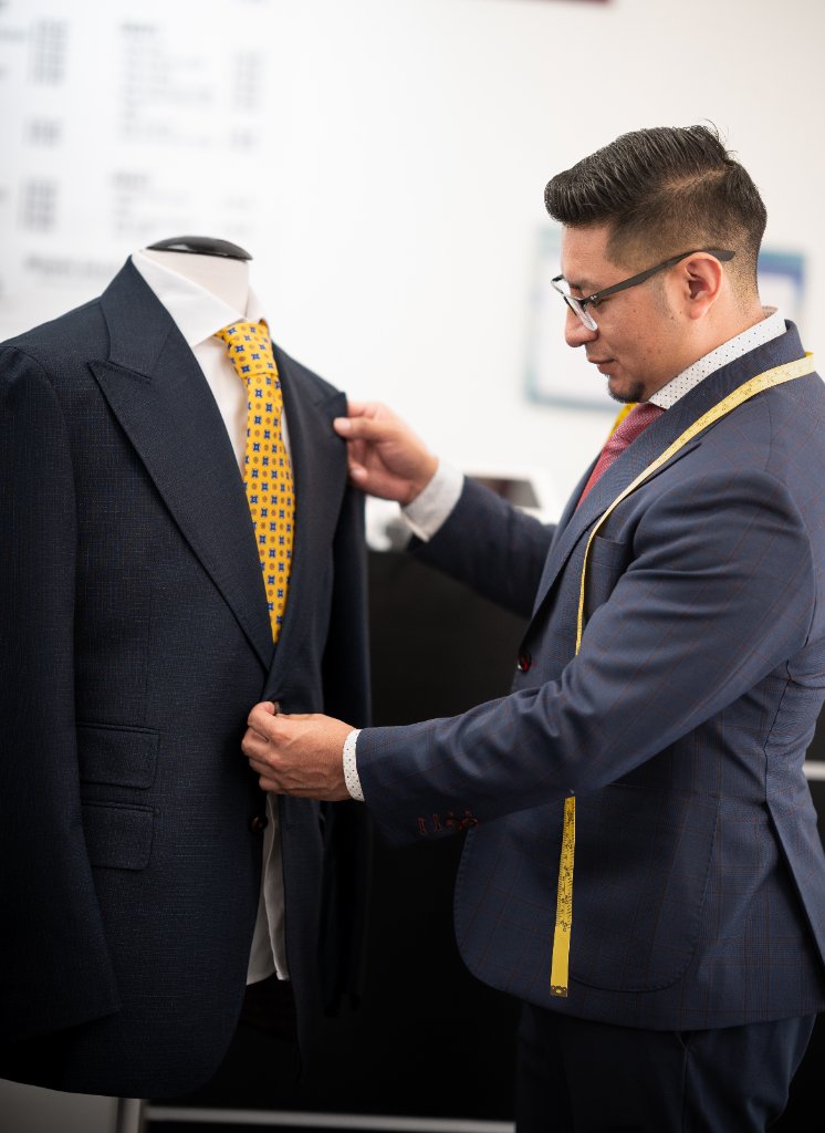 Renoj fitting a navy suit with gold tie
