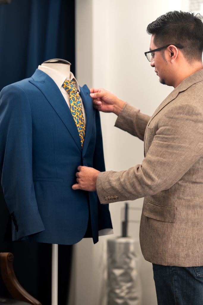 Renoj adjusting the lapel of a blue suit jacket