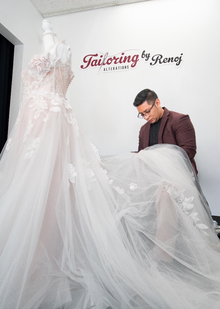 Renoj tailoring a white wedding gown on a mannequin