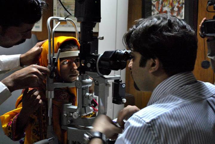 A child smiling brightly during an eye examination by a caring ophthalmologist