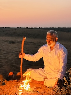 Ashraf Mystic sitting by a campfire in the Thar Desert at dusk