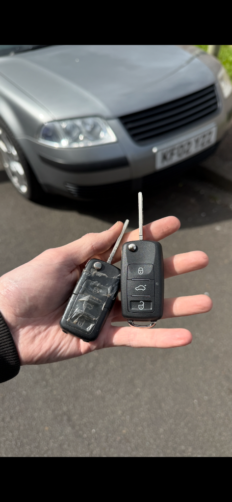 Worn original car key held together with tape next to a new replacement remote key