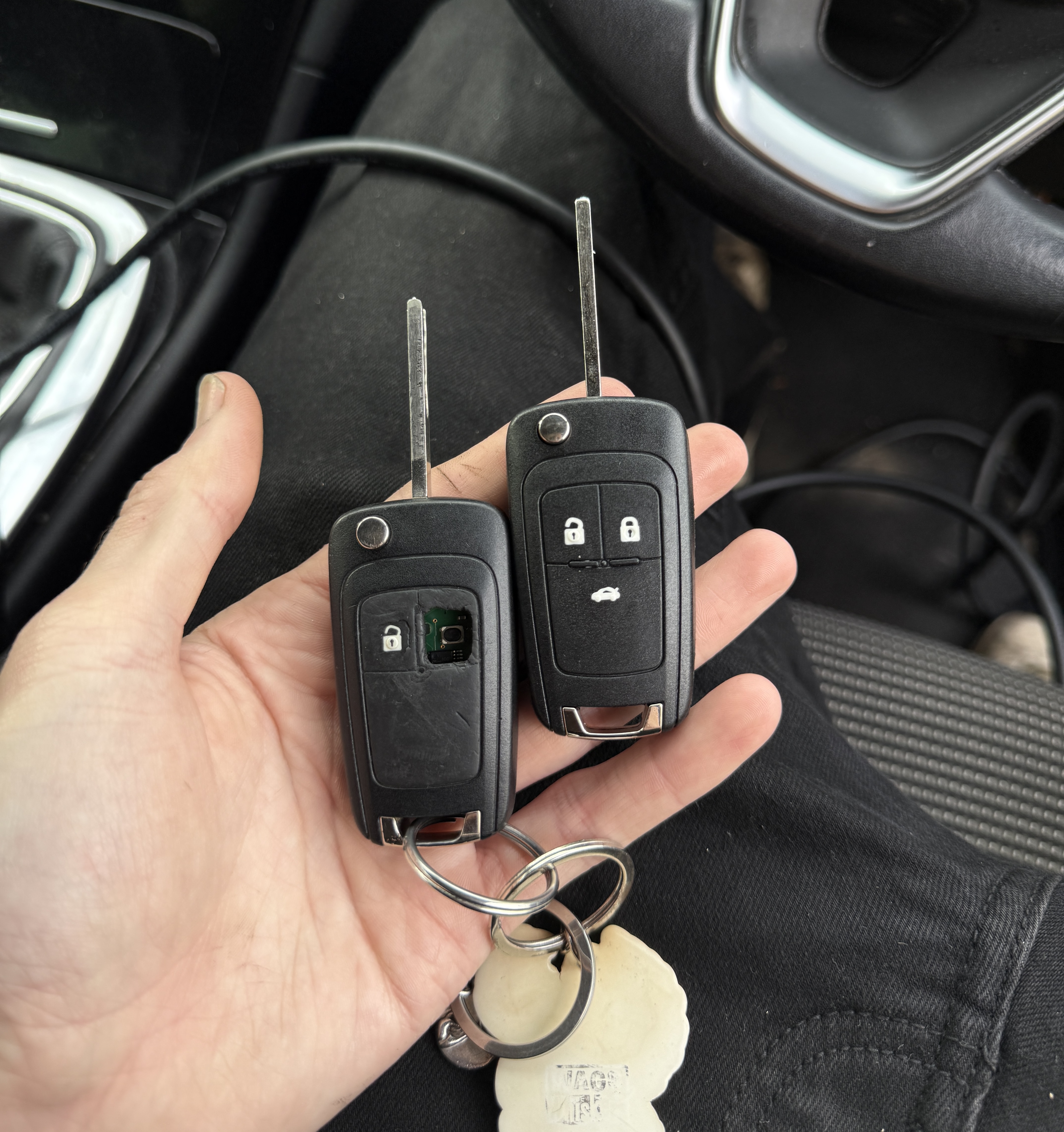Worn car key with exposed circuit board held alongside a brand new replacement remote key