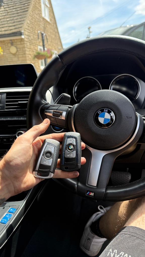 Two BMW key fobs held inside the M140i during key programming in Abingdon