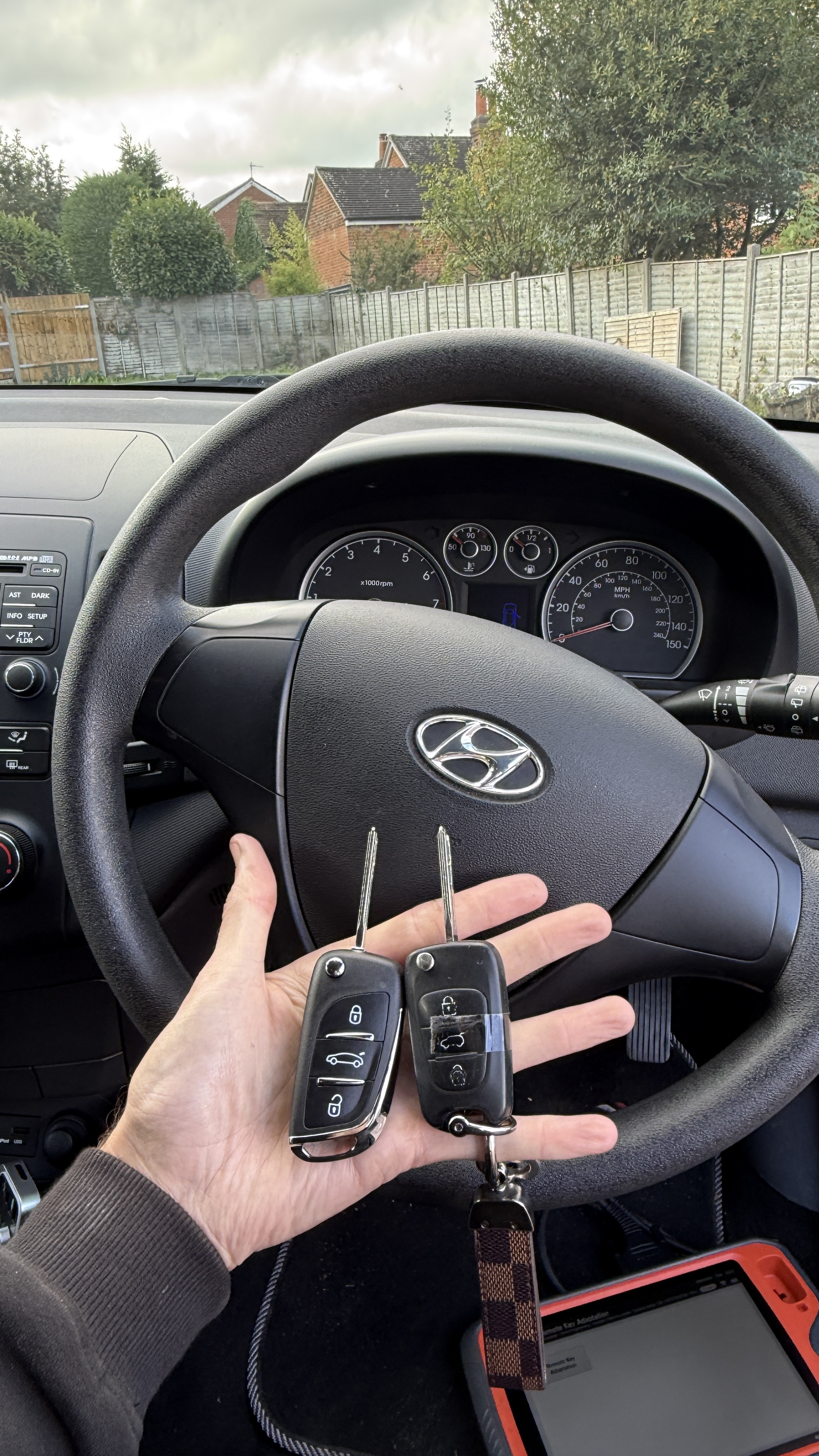 New and original Hyundai i30 keys held at the steering wheel with diagnostic equipment visible after spare key programming in Guildford