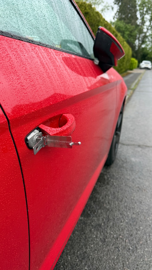 Professional non-destructive vehicle entry — a lockpick tool inserted into the door lock of a red car by KeyLogik auto locksmith